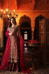 This exquisitely crafted bridal dress is made with utmost skills in zardozi hand embroidery. encrusted with colored semi precious stones, crystals and pearls. The shirt is made in crimson shade of tissue, paired with vintage jamavar in dull tilla