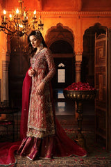 This exquisitely crafted bridal dress is made with utmost skills in zardozi hand embroidery. encrusted with colored semi precious stones, crystals and pearls. The shirt is made in crimson shade of tissue, paired with vintage jamavar in dull tilla 